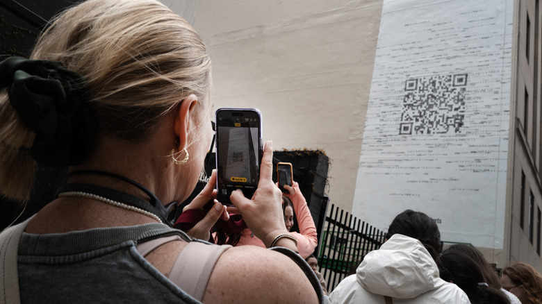 Person scanning a QR code positioned as wall art on a building.