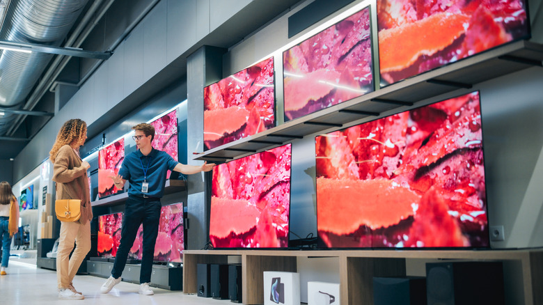 Woman discusses TVs with electronics store assistant..