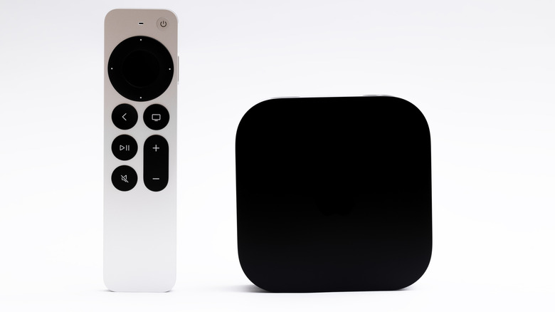 Apple TV 4K box standing upright next to the silver remote