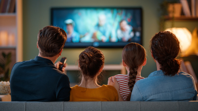 A family sitting on the sofa watching TV