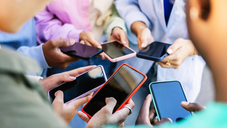 A group of people standing in circle using smartphones