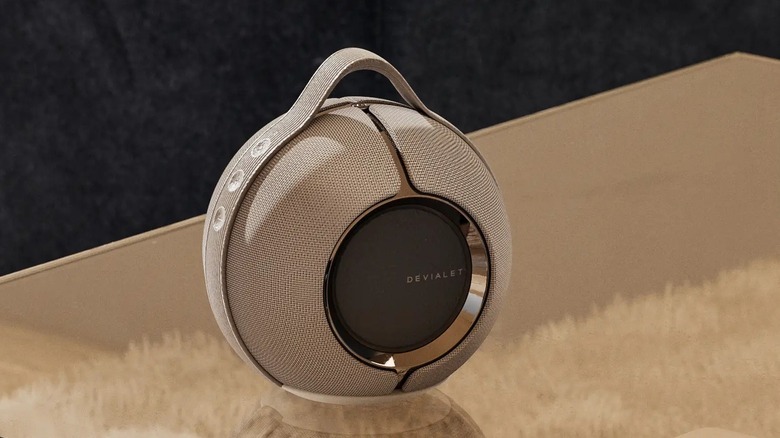 The Devialet Mania smart speaker on a glass table.