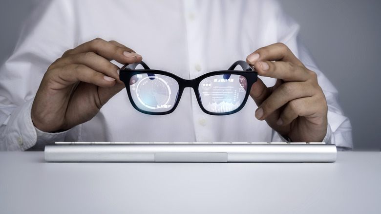 Hands holding smart glasses with a virtual interface displayed on them