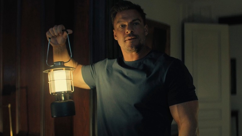 Alan Ritchson as Reacher holding a gas lamp