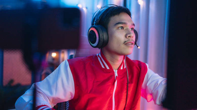 a young man PC gamer on a headset looking at his computer