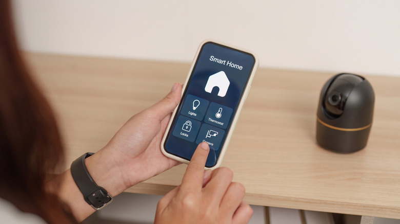 A person managing a smart home setup with a smartphone.