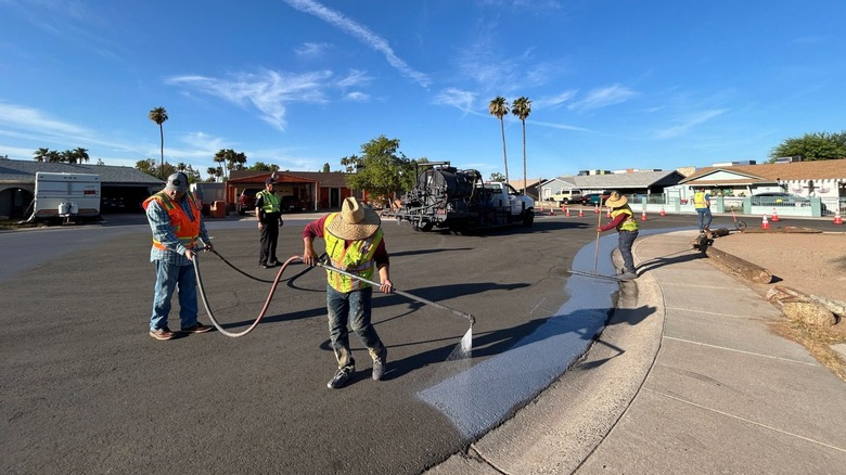 Workers painting a road in Phoenix with heat-reflecting cool pavement