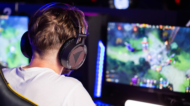 Back view of a person with headphones on playing a game on a computer
