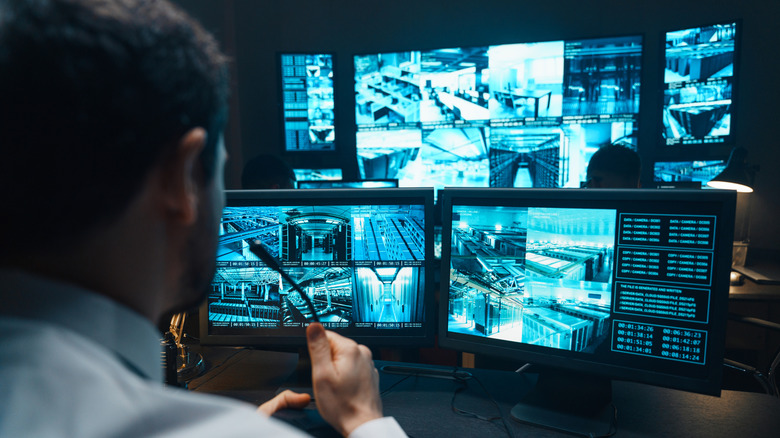 officer watching monitors with security footage on them