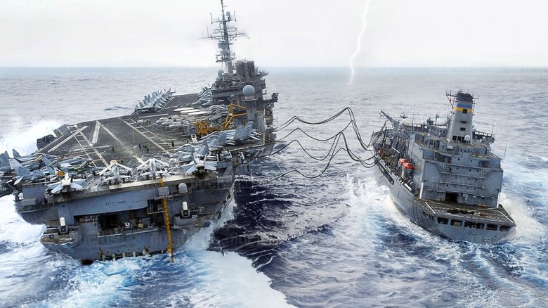 An oiler refuelling and resupplying an aircraft carrier during a thunderstorm