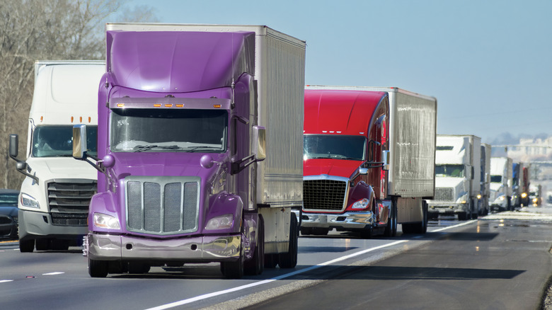 Many trucks driving along a busy highway.