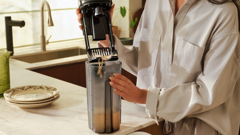 Woman cleaning Roborock's F25 Ace Pro dirt tank