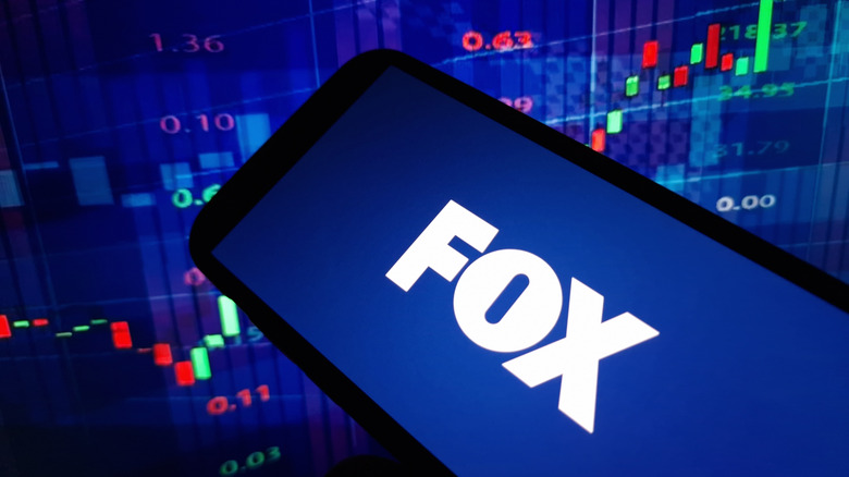Fox corporation logo on a smart phone in front of a graph