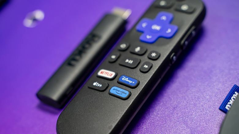 A Roku streaming stick beside a remote.
