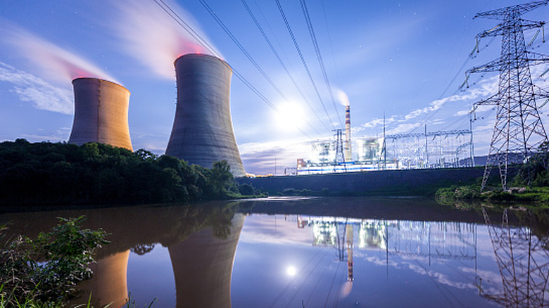 Nuclear powerplant seen with water source in the foreground at night