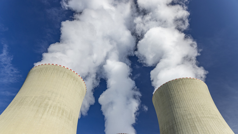Cooling towers releasing steam into a clear blue sky at a power complex