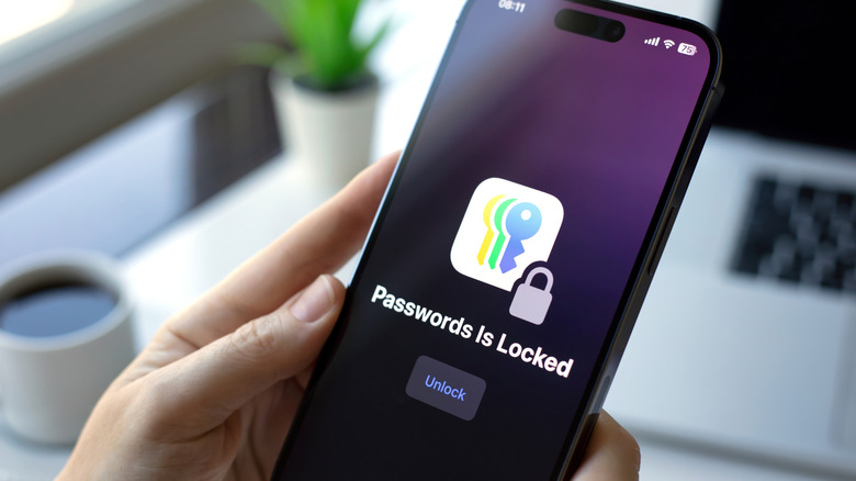 A hand holding an iPhone showing Passwords Is Locked.