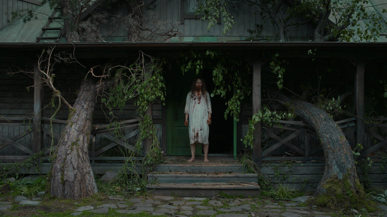 Saga standing on the porch in a bloody night gown