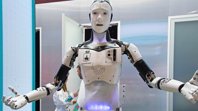 Humanoid Russian robot with arms out talking.