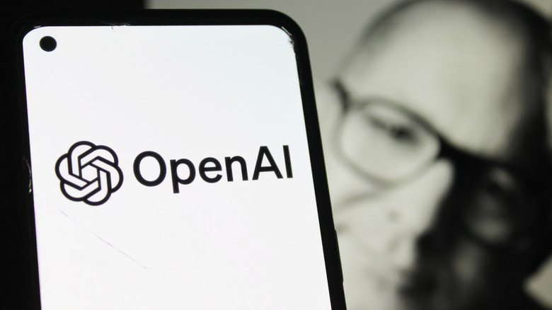 OpenAi ejecutando un teléfono con una foto de Jony Ive en el fondo