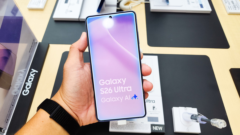 A person's hand holding a Samsung Galaxy S26 Ultra inside an electronics store.