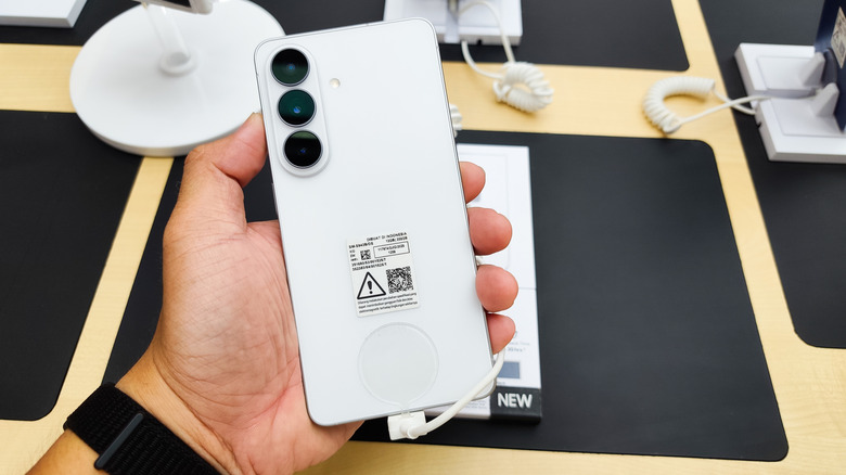 Person holding Samsung Galaxy S26 ultra smartphone plugged into table
