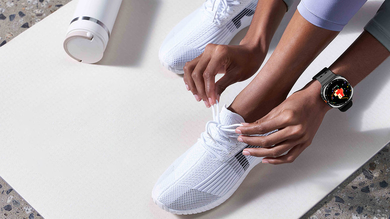 A person tying their shoe on a yoga mat while wearing the Samsung Galaxy Ultra.