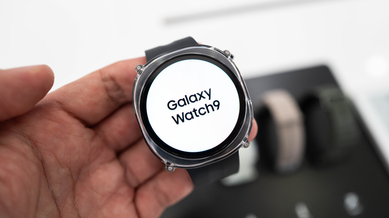 A Samsung Galaxy Watch 9 being held in a user's hand, it appears as though the user is inside a store