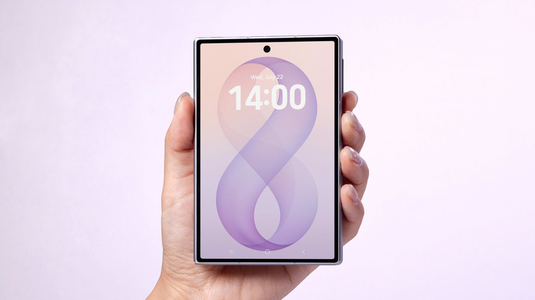 Hand holding a Samsung Galaxy Z Fold 8 on a pink background
