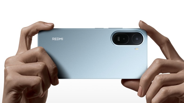 Person holding Xiaomi Redmi A7 Pro to take a picture in front of a white background