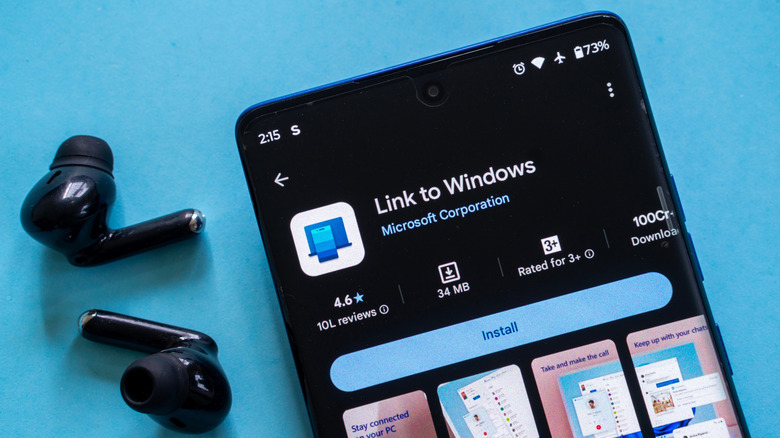 A pair of earbuds sitting next to a phone with the Link to Windows app open.