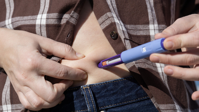 Someone injecting a mock GLP-1 treatment into their abdomen.