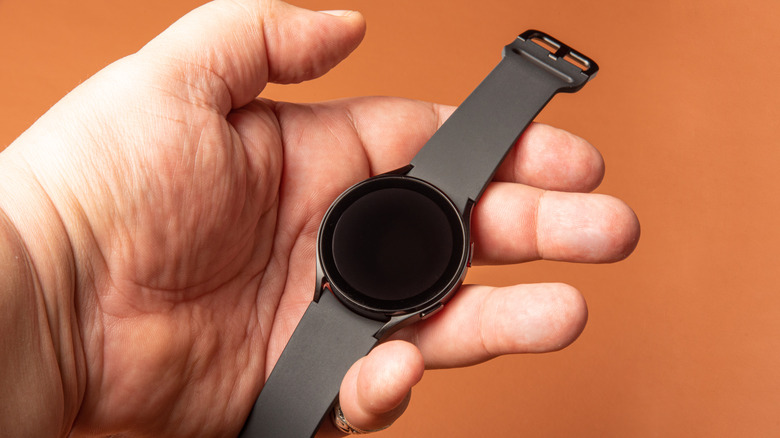 A hand holding a Samsung Galaxy Watch 4