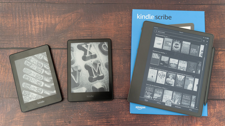 Various Amazon Kindle models on a table, including the Kindle Scribe.