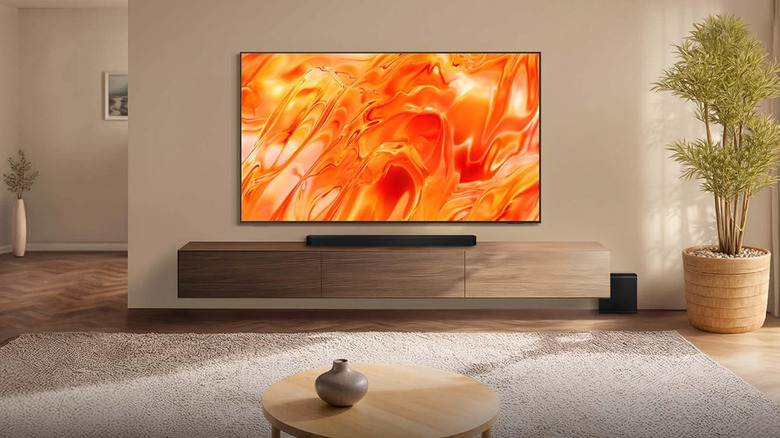 The Samsung Neo QLED QN70H TV mounted on a wall with an orange colorful image onscreen