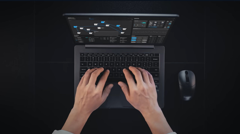 An aerial view shows  man typing on a Samsung Galaxy Book6 Enterprise against a black background.