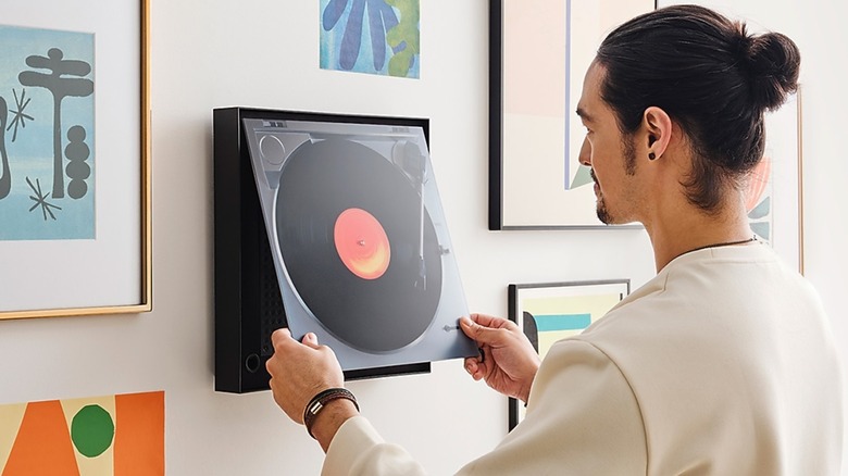 Man hanging Music Frame LS-60D wireless speaker picture frame with picture of record player turntable