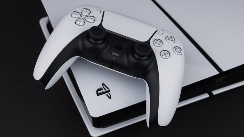 A white Playstation 5 Dual Sense controller sitting on top of a white PlayStation 5 console
