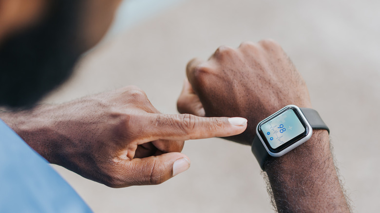 A man looks and points at his smartwatch.