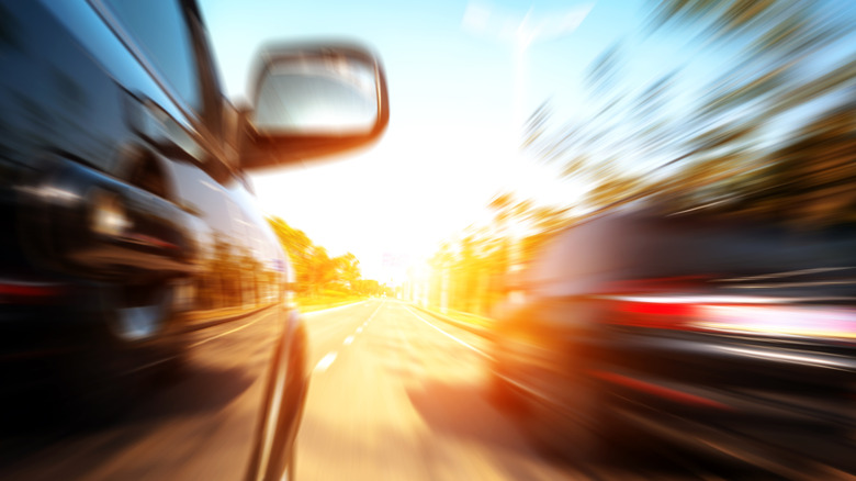 A car overtaking passing another car in blurred image.