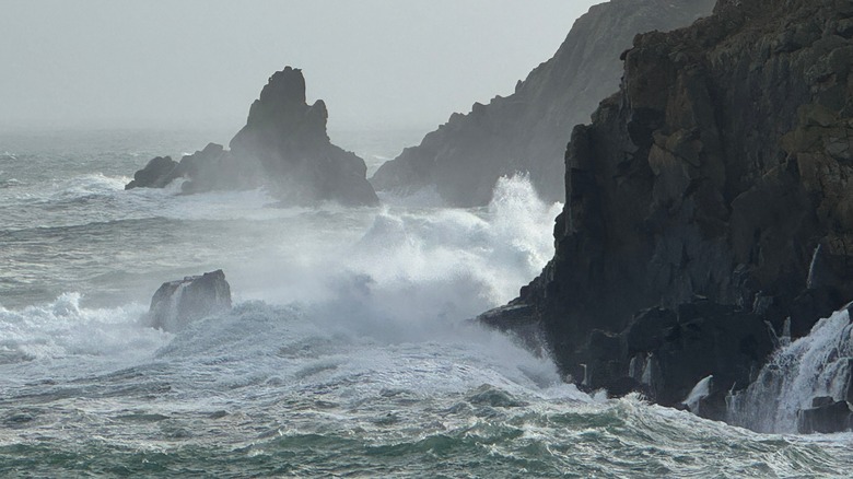 Swell waves crashing into a cliffside.
