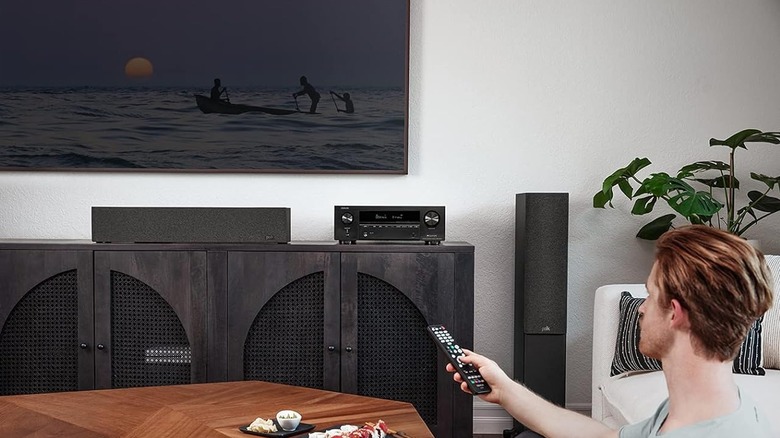 A person aiming a remote at the Denon AVR-X7100H AV Receiver