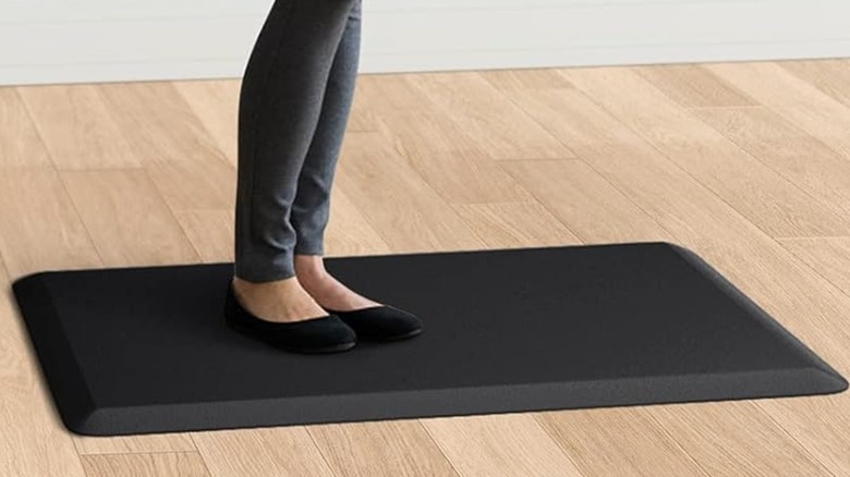 A worker at a standing desk using a KitchenClouds anti fatigue rug.