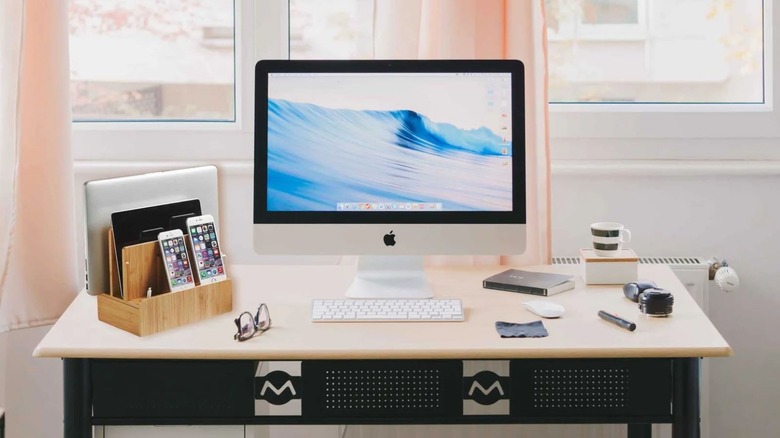 A desk with a GUS all in one charging station with multiple gadgets plugged in.