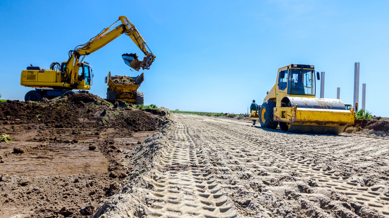 Compacted soil used as a road foundation with heavy machinery in operation.