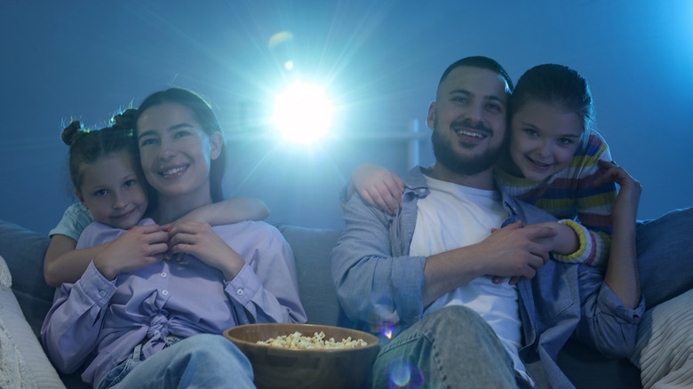 a happy family watching a movie on a projector