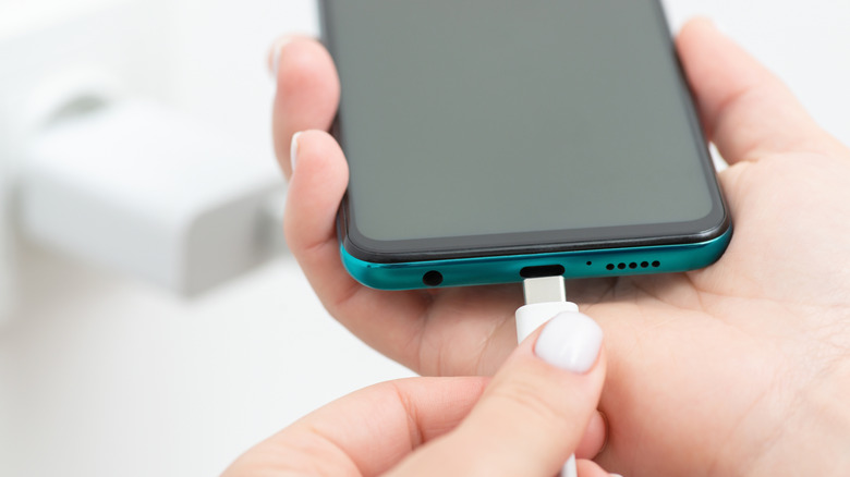 Person plugging charging cable into phone