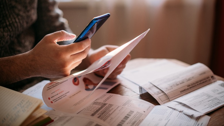 A person pays bills on a phone