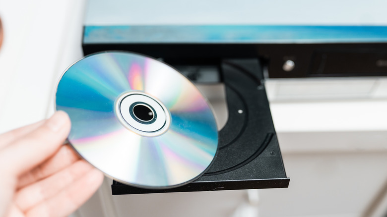 A person inserts a physical media disc into a drive.