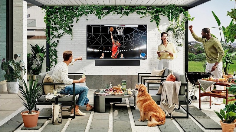 Samsung The Terrace TV mounted on wall outside with people watching.